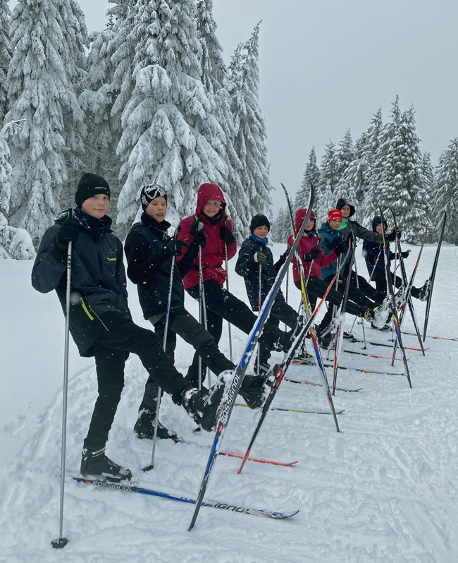 Fröhliche Schüler auf Skiern im Schnee