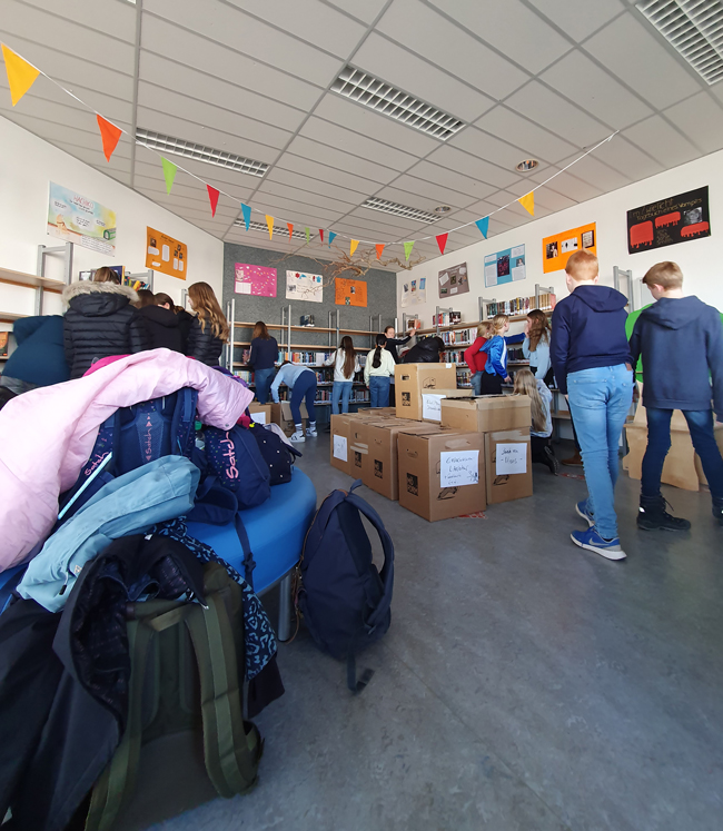 Schüler packen Bücher der Bibliothek in Umzugskartons