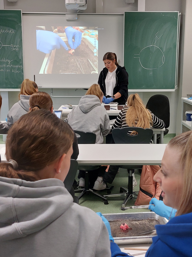 Lehrerin zeigt Schülern im Klassenraum das Präparieren