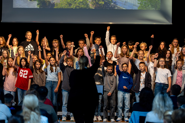 Chorschüler strecken singend Hände in die Luft 