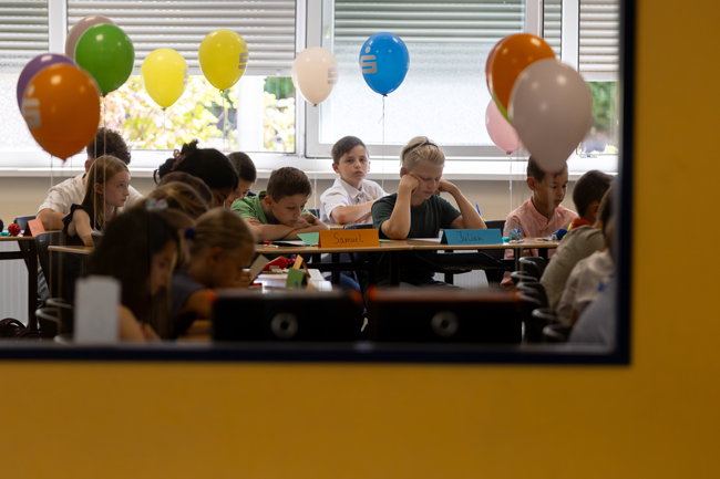 Schüler im Klassenraum sitzend mit Luftballons