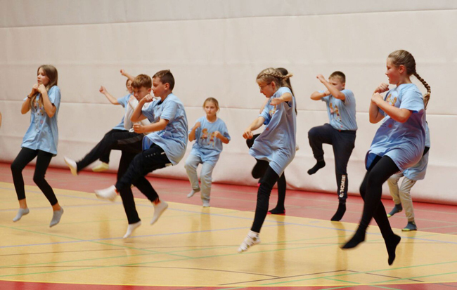 Schülergruppe in hellblauen T-Shirts übt Kampfsport