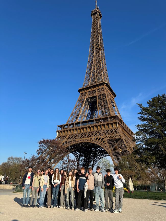 Schülergruppe vor dem Eiffelturm unter blauem Himmel