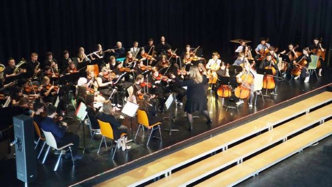 Blick von oben auf Bühne mit Schülern, die Streich- und Blasinstrumente spielen