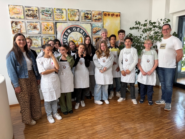 Schülergruppe mit Lehrern vor Schildern der Bäckerei 