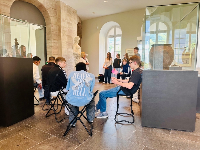 Schüler sitzen im Kreis in einem Museumsraum