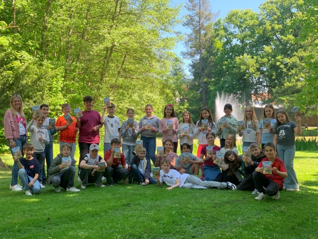 Gruppenbild einer Klasse im Grünen mit Büchern in der Hand