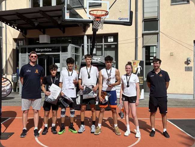 Gruppenbild auf dem Basketballplatz vor dem Korb mit Urkunde und Medaillen