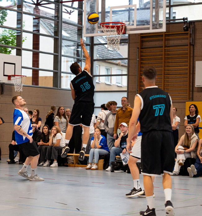 Lehrer der GSO beim Spiel, wobei einer gerade einen Ball in den Korb wirft