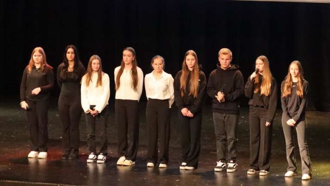 Neun Schülerinnen und Schüler auf der Bühne nebeneinander stehend mit Mikros