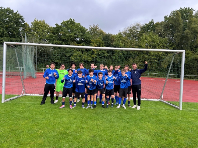 Jungenfussballmannschaft mit Trainer im Tor jubelnd