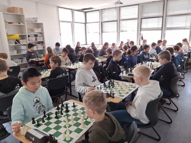Klassenraum voller Schüler, die an Schachbrettern sitzen